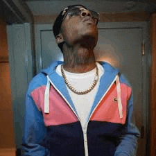 a man wearing sunglasses and a pink and blue jacket is looking up .