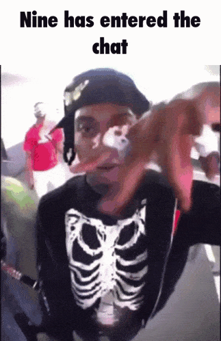 a man wearing a skeleton shirt is pointing at the camera with the caption " nine has entered the chat "