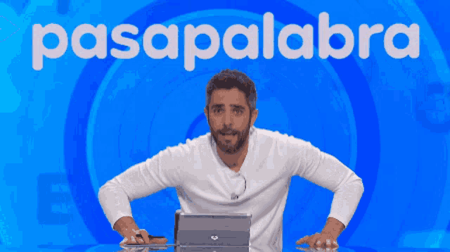 a man sits in front of a blue background with the word pasapalabra