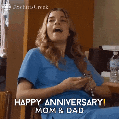 a woman in scrubs says happy anniversary mom and dad on her phone
