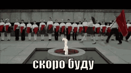 a group of children are standing in front of a flame in a fountain holding red flags .