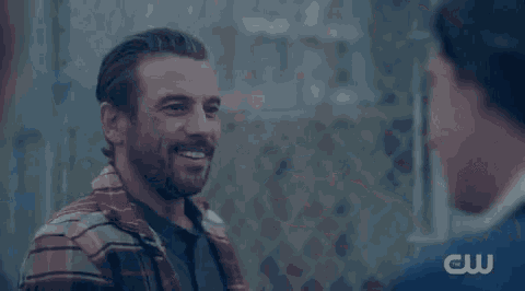 a man with a beard is smiling at another man .