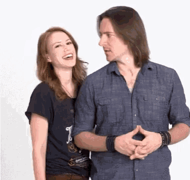 a man and a woman are standing next to each other laughing .