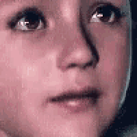a close up of a child 's face with a sad look on his face .