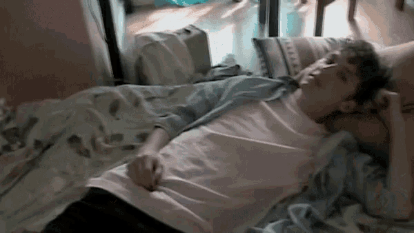 a man in a white shirt is laying on a bed with a pillow .