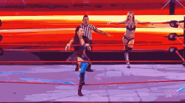 two women are wrestling in a ring with a referee and a w logo