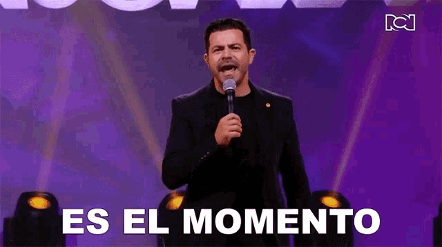 a man in a suit is holding a microphone and singing into it .