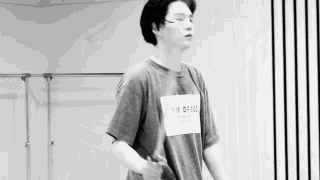 a black and white photo of a young man in a t-shirt jumping rope .