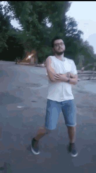 a man with a beard and glasses is standing with his arms crossed
