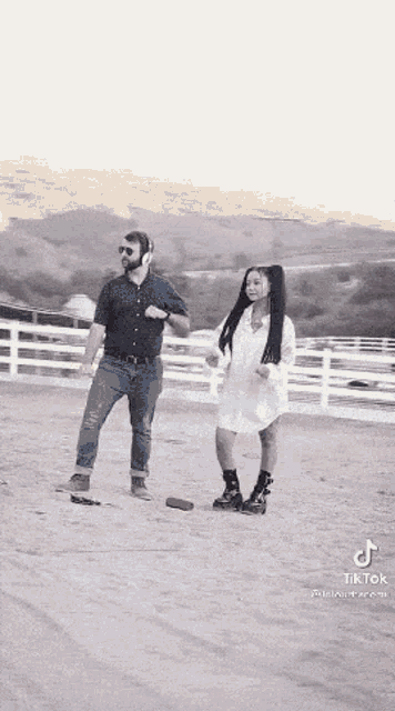 a man and a woman are dancing in a dirt field while wearing headphones .