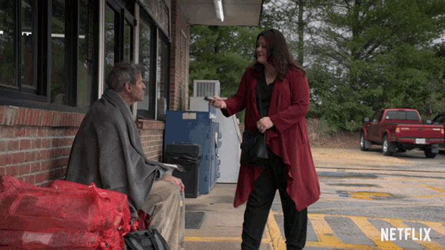 a woman in a red coat talks to a man in a wheelchair