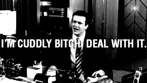 a man in a suit and tie is sitting at a desk with the words i 'm cuddly bitch deal with it