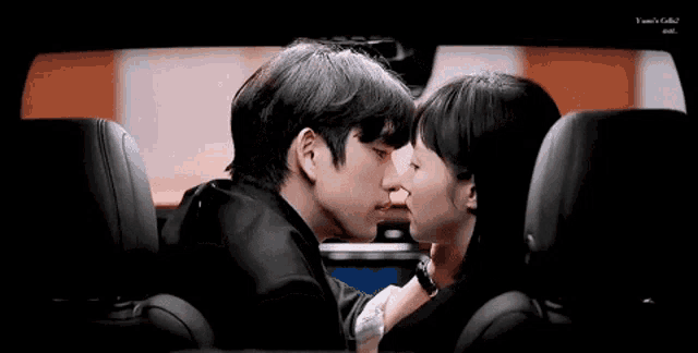 a man and woman are kissing in a car .
