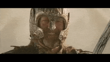 a man wearing a helmet and holding a sword is smiling .