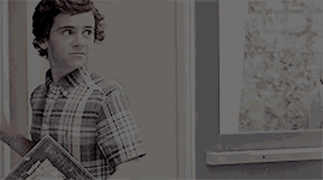 a young man in a plaid shirt is standing next to a door .