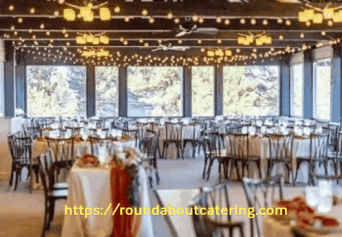 a large room with tables and chairs set up for a wedding reception with the website https://roundaboutcatering.com in the corner
