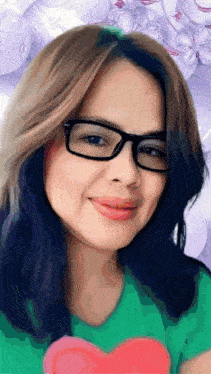 a woman wearing glasses and a green shirt is smiling