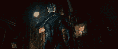 a man in a black suit is holding a gun in the dark .