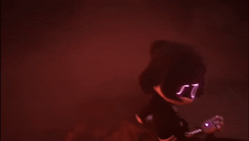a blurry picture of a person in a dark room with a red light behind them .