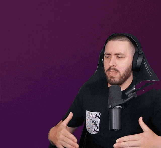 a man wearing headphones and a black shirt with a playing card pocket is talking into a microphone