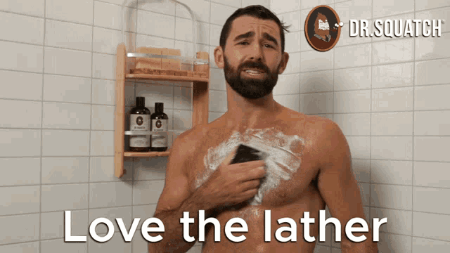 a shirtless man is taking a shower with the words love the lather