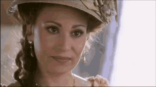 a woman wearing a hat is smiling and looking at the camera .