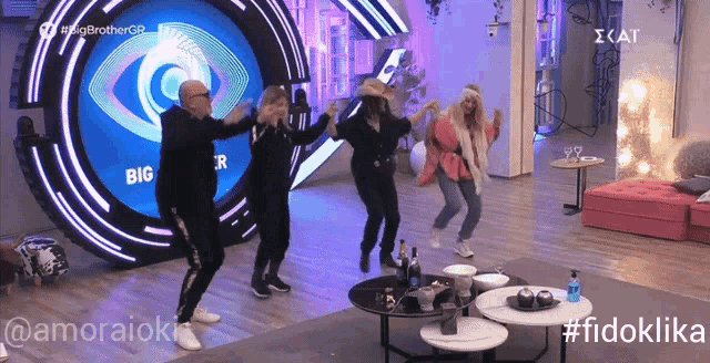 a group of people are dancing in front of a sign that says big brother