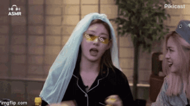 a woman with a blue scarf around her head is talking to another woman with yellow glasses