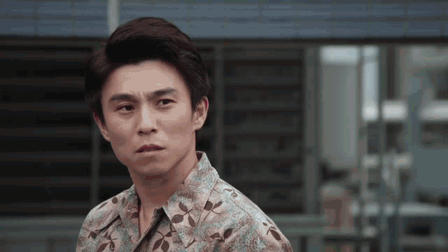 a man in a floral shirt is looking at the camera