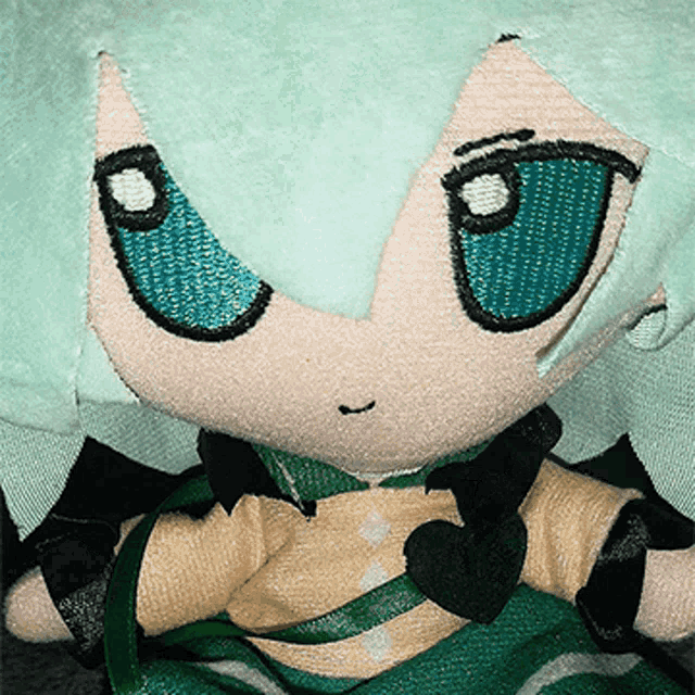 a close up of a stuffed doll with green hair and blue eyes