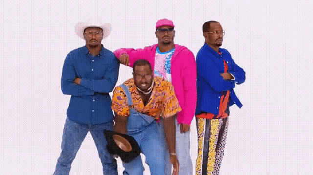 a group of men standing next to each other wearing colorful clothes .