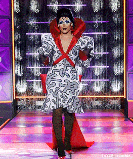 a drag queen is walking down the runway wearing a very colorful dress .