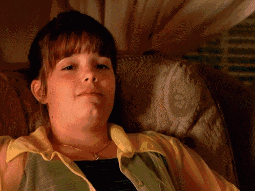 a woman in a yellow and green shirt is laying on a chair