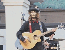 a man in a top hat and suspenders is playing a guitar .