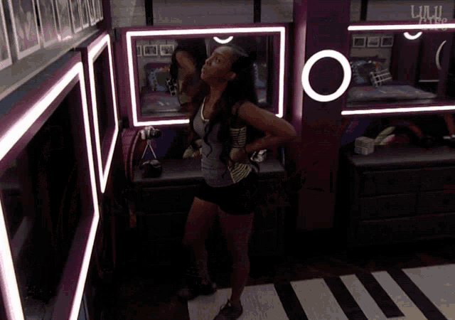 a woman stands in front of a mirror in a room that says ' ulw ' on it
