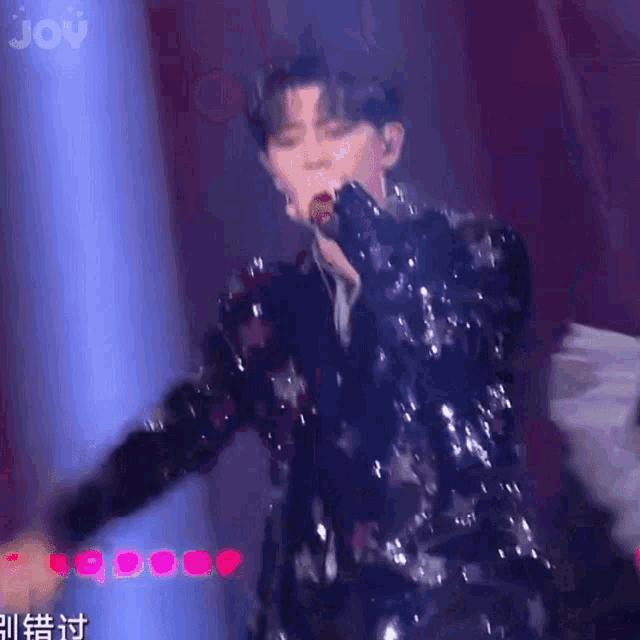 a man in a sequined jacket is singing into a microphone .