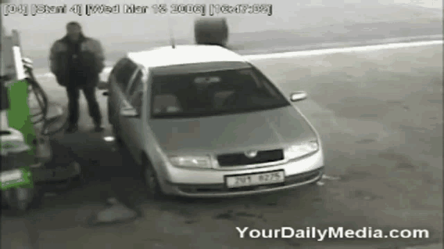 a man is standing next to a silver car that says yourdailymedia.com on the bottom of the screen