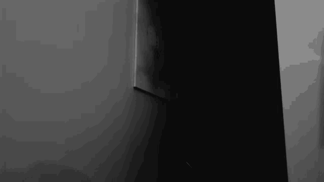 a dark room with a white wall and a black corner