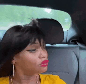 a woman in a yellow shirt is sitting in the back of a car