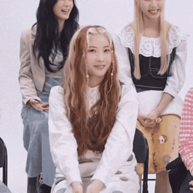 a group of women are sitting in chairs and one of them is wearing a white shirt with polka dots on it