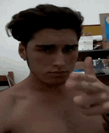 a shirtless man points at the camera with his finger