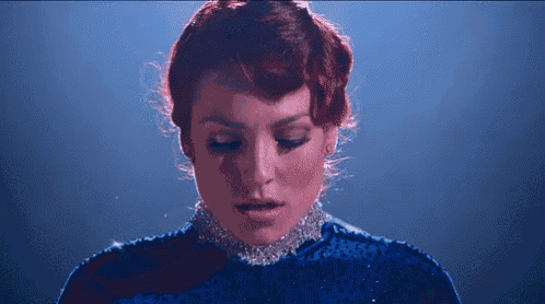 a woman with red hair is wearing a blue dress and a choker .