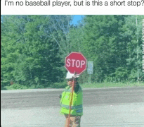 a man in a yellow vest is standing next to a stop sign .