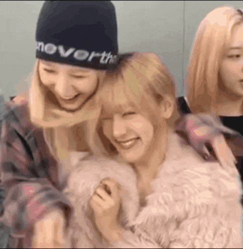 two girls are hugging each other and one of them is wearing a black hat .