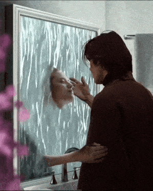 a man is touching his face in front of a mirror