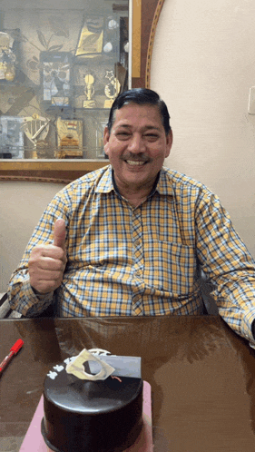 a man giving a thumbs up next to a cake