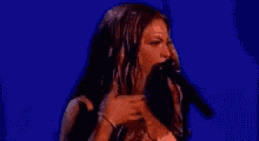 a woman in a red dress is singing into a microphone on a stage .