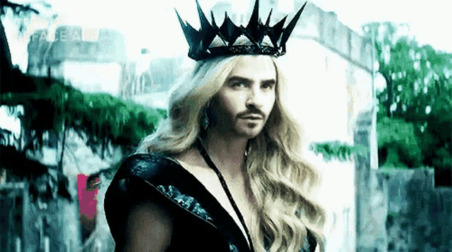 a man with long blonde hair and a crown is wearing a black dress .