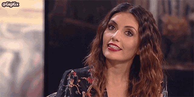 a woman with curly hair is smiling and looking at the camera with the hashtag gigigx in the corner