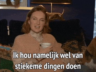 a woman sits on a couch with a cup of coffee and says ik hou namelijk wel van